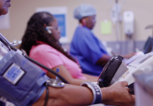 A diverse group of low-income individuals undergoing health check-ups in a modern clinic, focusing on advanced health monitoring devices and friendly healthcare providers. Include details of their blood pressure being measured in a calm environment, representing hope and care for cardiovascular health improvements.